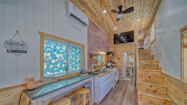 Un intérieur en bois comprenant un coin cuisine, des tabourets de bar et un escalier.