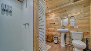 Une salle de bain avec des murs en bois, un lavabo, des toilettes et une douche.
