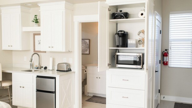 Une cuisine moderne avec des meubles blancs, un four à micro-ondes LG, une machine à café et un grille-pain.