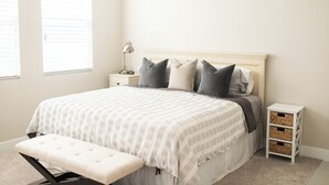 Une chambre bien rangée, avec un lit, des tables de chevet, une lampe et des boîtes de rangement.