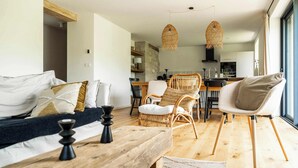 A modern living room with a wooden bench, wicker chairs, and a dining area with a table and chairs. - Sauna & bain nordique - Vue panoramique - 8 pers (Prémanon)