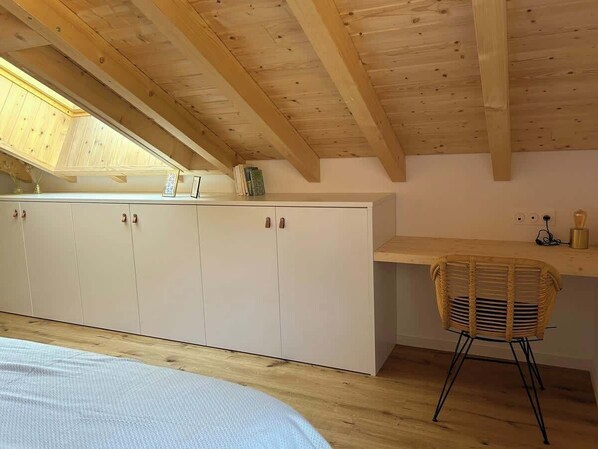 A bedroom with a wooden ceiling, a bed, a wardrobe, a desk with a chair, and a skylight. - Sauna & bain nordique - Vue panoramique - 8 pers (Prémanon)