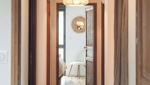 A hallway with wooden flooring, a hanging light fixture, and a door leading to a room. - Sauna & bain nordique - Vue panoramique - 8 pers (Prémanon)