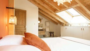 A bedroom with a skylight, wooden beams, a bed with white bedding, a wooden wardrobe, and a small stool. - Sauna & bain nordique - Vue panoramique - 8 pers (Prémanon)