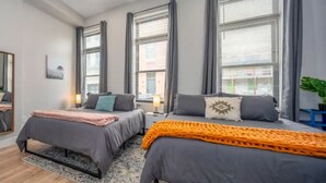 A modern bedroom with two beds, large windows, and a mirror. - OTR, 3 Lux Queens, Two 55in TVs,  by TQL, Findlay Mkt, FREE Light Rail, Sleeps 7 (Cincinnati)