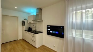 A modern kitchen with a built-in oven, a coffee machine, and a wall-mounted TV displaying the Google Play app. - Park View Studio - Features Free Wifi, Bright Furnishings and Modern Facilities (Nijmegen)