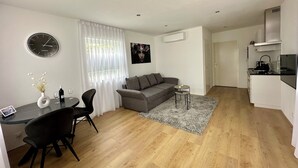 A modern apartment with a dining area, a living room with a grey sofa, a kitchen with white cabinets, and a wooden floor. - Park View Studio - Features Free Wifi, Bright Furnishings and Modern Facilities (Nijmegen)