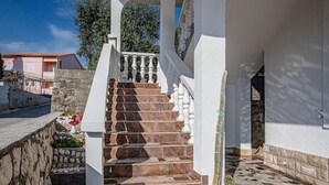 Un escalier en pierre mène à un balcon blanc agrémenté d’une balustrade.