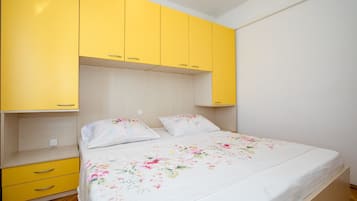 Un dormitorio con una cama, dos almohadas, una mesita de noche y armarios amarillos.