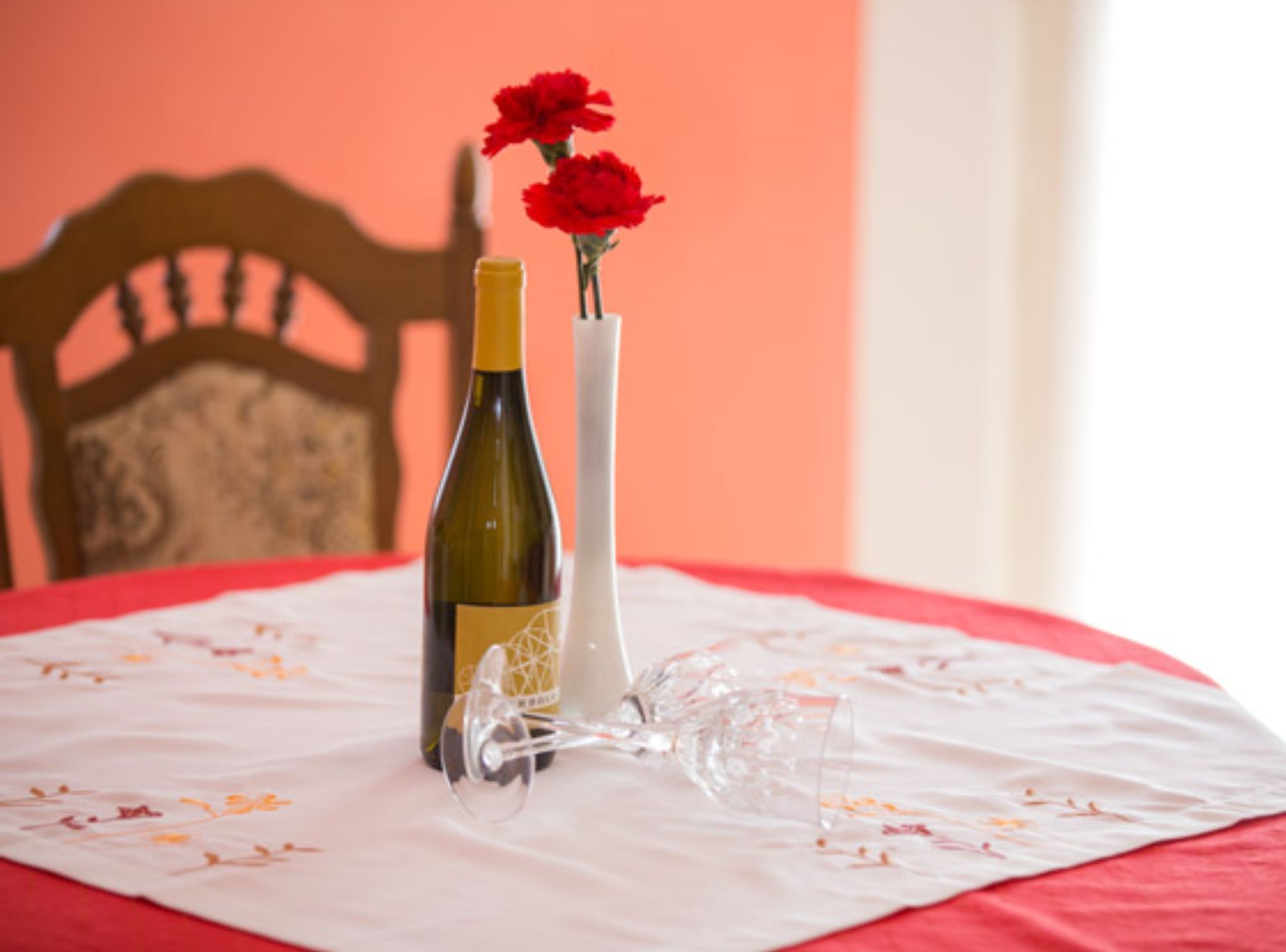 Ein Tisch mit einer Weinflasche und einer Blumenvase auf einer Tischdecke.