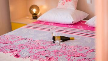 Una cama con una colcha de estampado floral, una botella de champán y una copa sobre la cama.