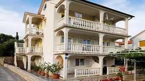 Un immeuble à plusieurs étages, doté de balcons, de plantes en pot et d’un mur en pierre.