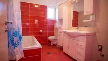 A bathroom with red tiles, a white bathtub, a white sink, and a white toilet.