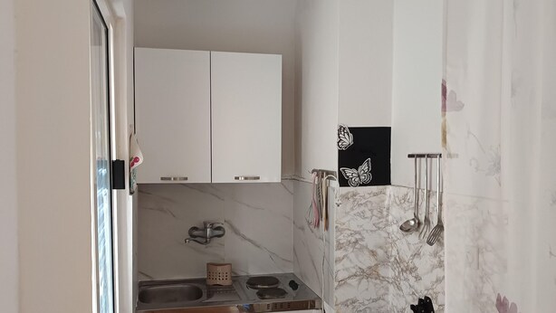 Une cuisine compacte avec des meubles blancs, une cuisinière encastrée et un pare-feu en marbre.