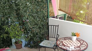 Un balcon avec une chaise, une petite table et un pot de fleurs.