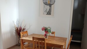 Un coin repas avec une table et des chaises en bois, un vase rempli de fleurs et une œuvre d’art encadrée accrochée au mur.
