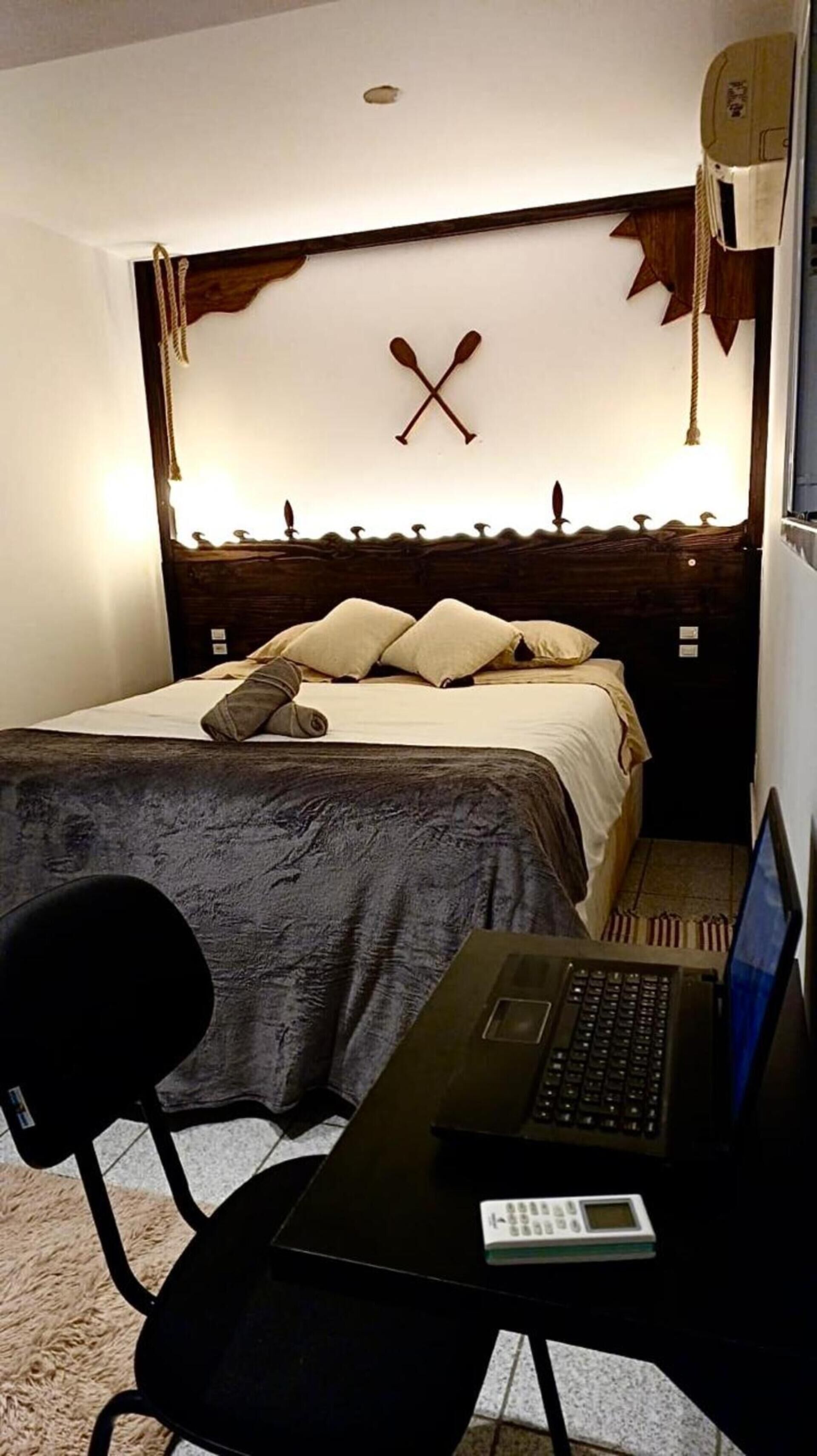 Una habitación de hotel con una cama, un escritorio con una computadora portátil y una silla.