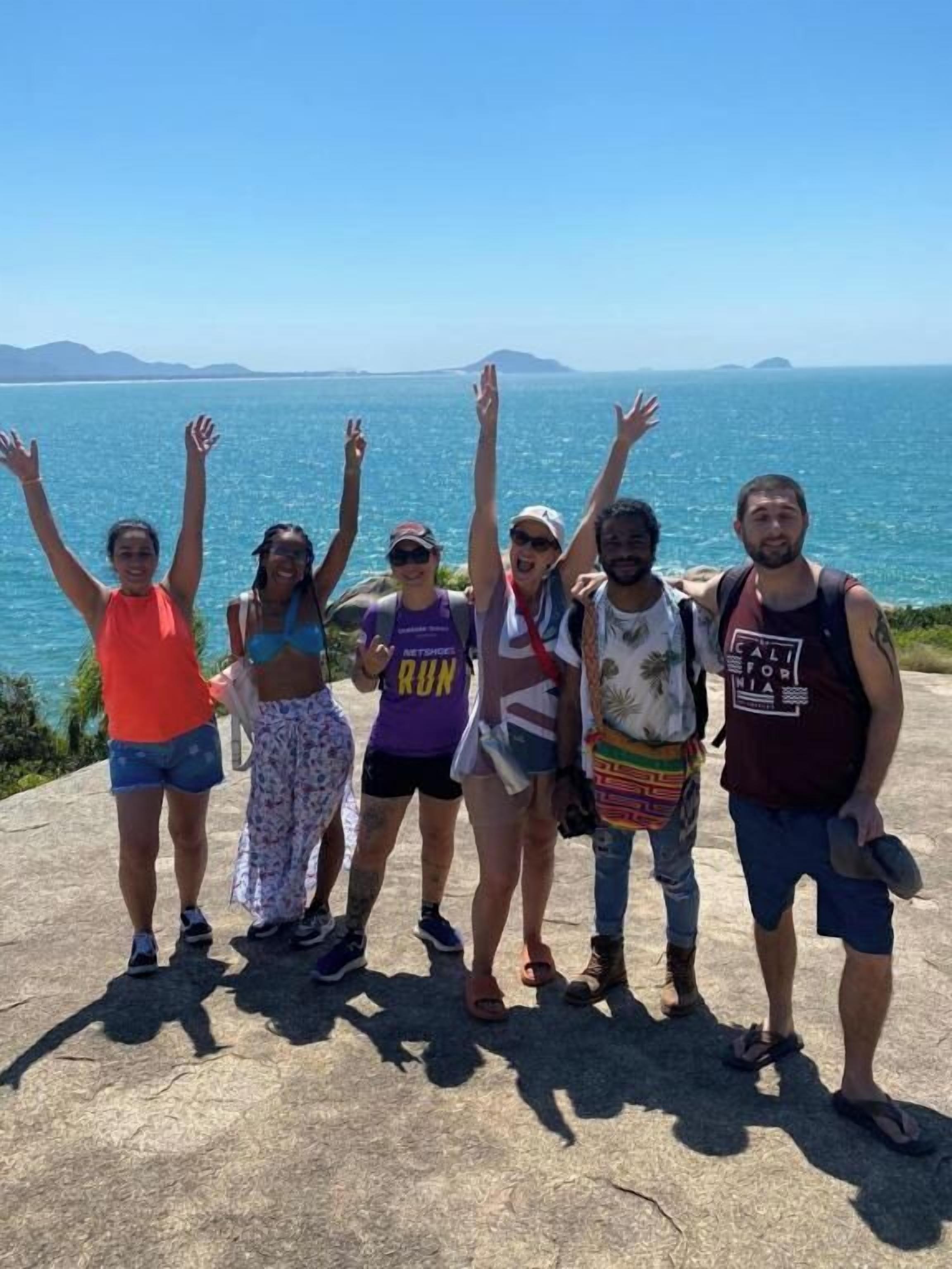 A group of people standing on a concrete ledge with a view of the ocean and distant islands.