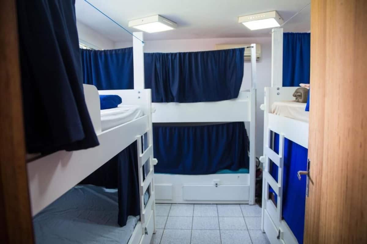 A narrow room with bunk beds, a small window, and a door.