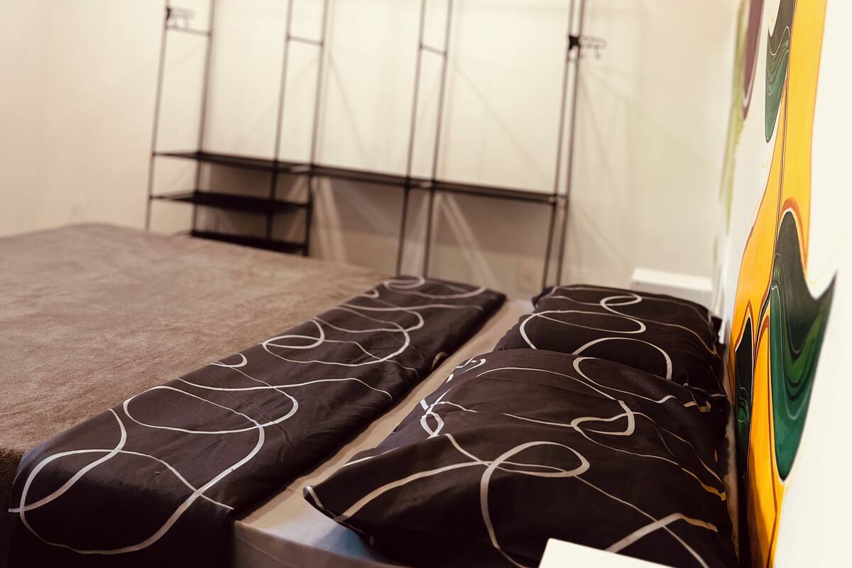 A room with a bed, a wardrobe, and an air conditioning unit.