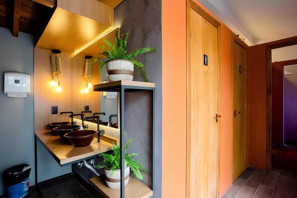 A modern bathroom with a wooden vanity, multiple sinks, and a towel rack. - Island Vibe Nomads - Adventure Hostels (Florianópolis)