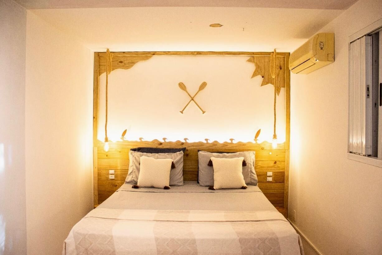 Un dormitorio con cabecera de madera, dos almohadas y una cama con colcha a cuadros.