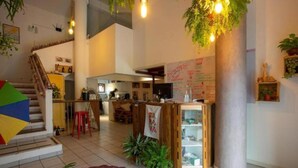 A spacious interior with a staircase, a kitchen area, and a counter with a menu board. - Island Vibe Nomads - Adventure Hostels (Florianópolis)