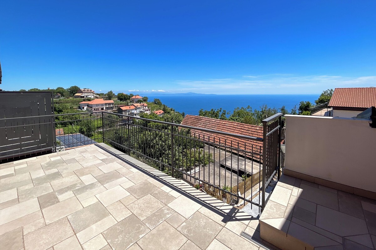 A balcony with a view of the sea and surrounding buildings.
