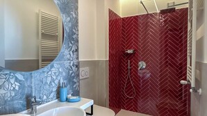 A modern bathroom with two sinks, a large mirror, and a shower with red herring-patterned tiles. - CASA MILLY (Agerola)
