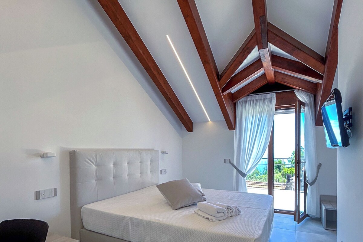 A bedroom with a bed, a desk, and a TV mounted on the wall.