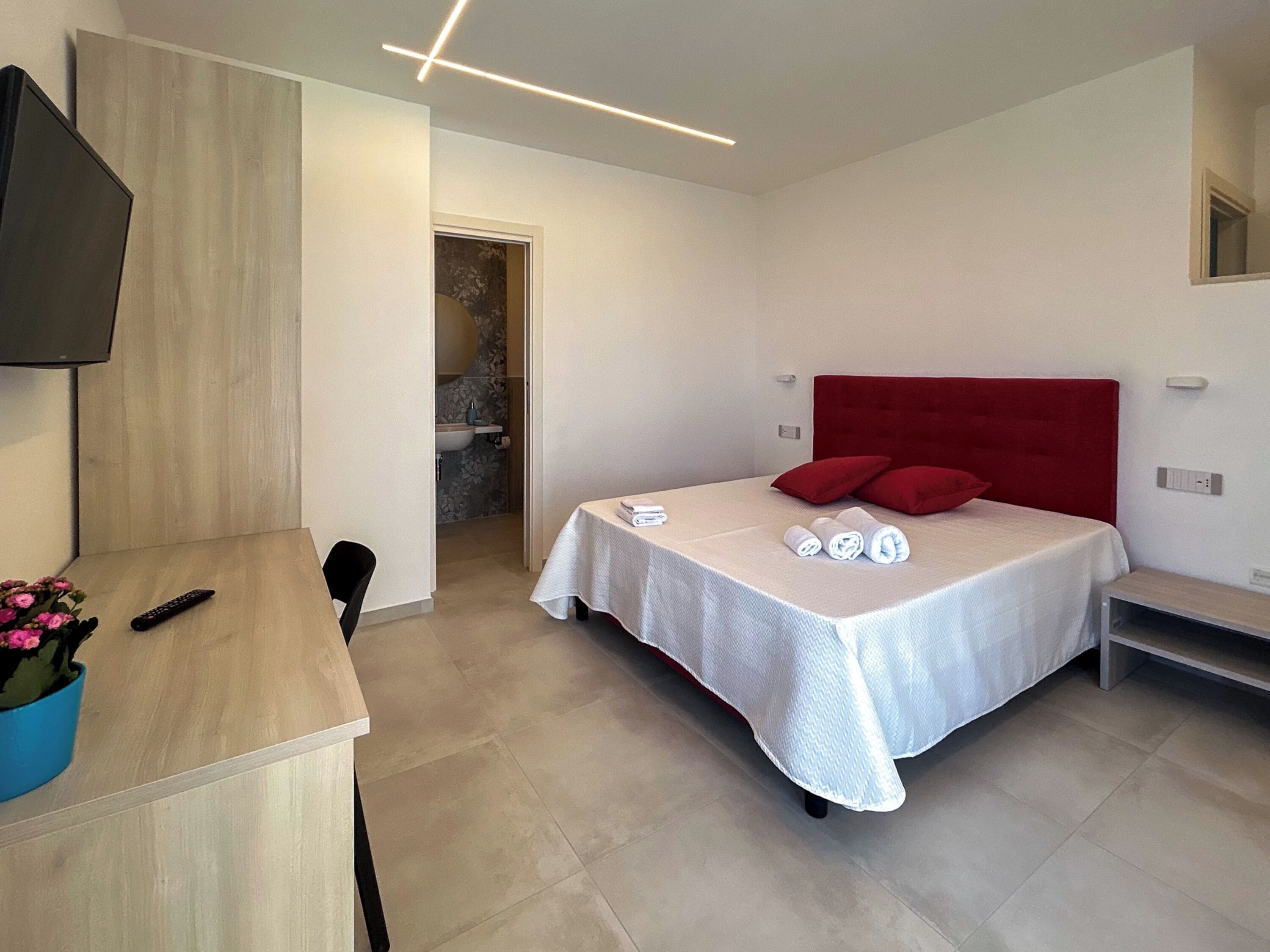 A modern hotel room with a bed, a desk, and a TV.