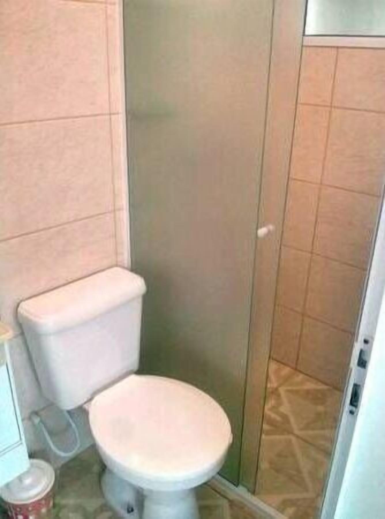 Une petite salle de bain fermée, équipée de toilettes et d’une cabine de douche.