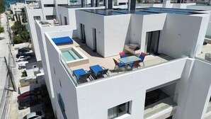 En modern takterrass med pool, utomhusmöbler och utsikt över havet.