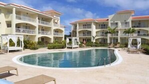 A resort with a large pool, multiple balconies, and a clear sky.