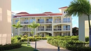 A multi-story hotel with balconies, a central courtyard, and palm trees.