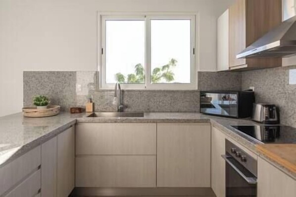 Cocina moderna con encimera de granito, electrodomésticos de acero inoxidable y una ventana sobre el fregadero.