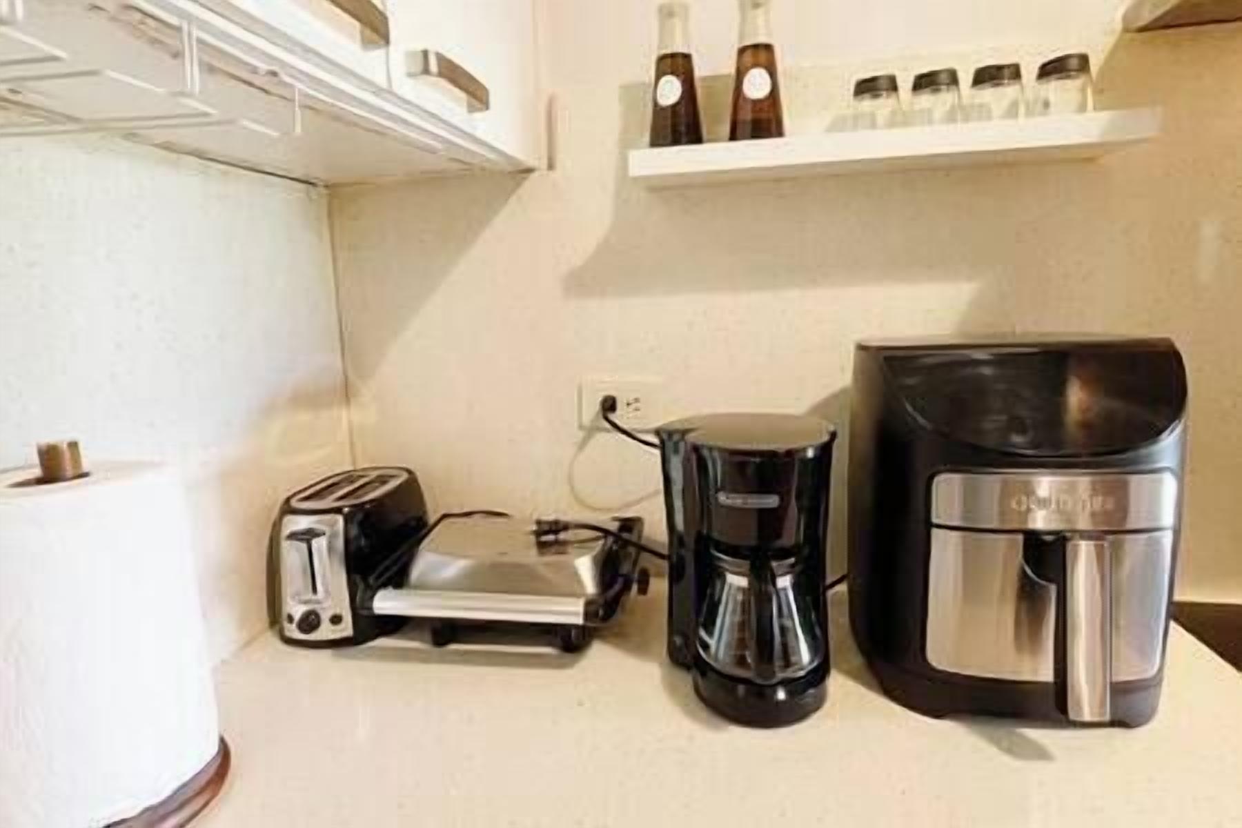 A kitchenette with a toaster, a coffee maker, and a kettle on the counter.