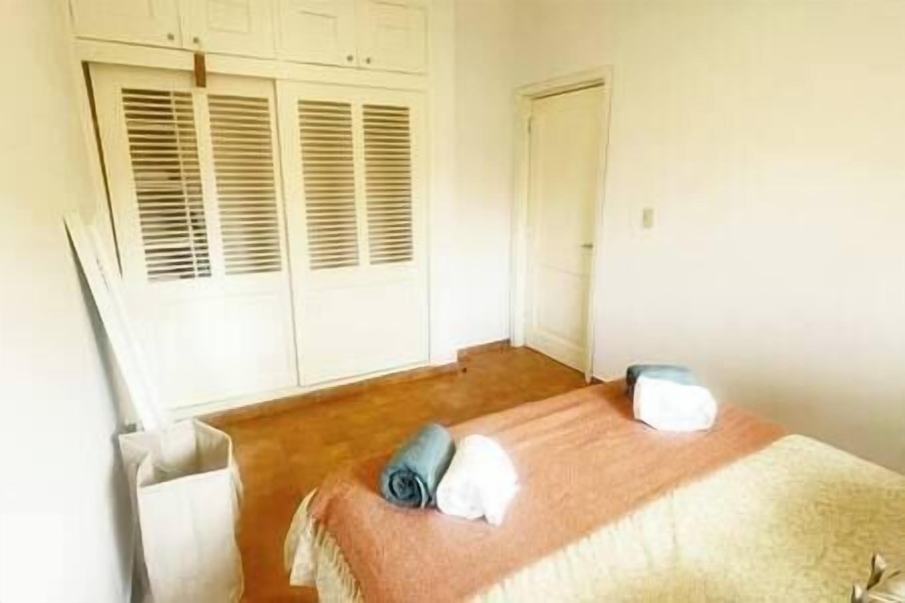 A room with two beds, a wooden floor, and white walls.