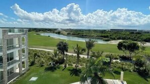 Um edifício moderno com fachada de vidro, com vista para um rio e um campo de golfe.