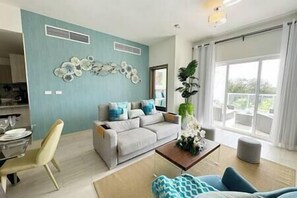Una sala de estar moderna con un sofá gris, una mesa de centro y un comedor con una silla y una mesa.