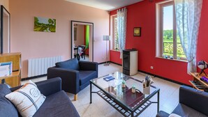 A living room with a sofa, a glass coffee table, a TV, and a radiator.