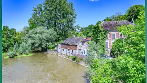 A riverside view with buildings and lush greenery.