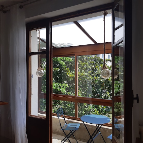 Um quarto com uma janela grande, uma mesa azul e duas cadeiras.