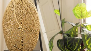 A decorative woven vase on a table, a black-framed mirror leaning against a white door, and a potted plant with variegated leaves. - Dimora Talenti (Polignano a Mare)