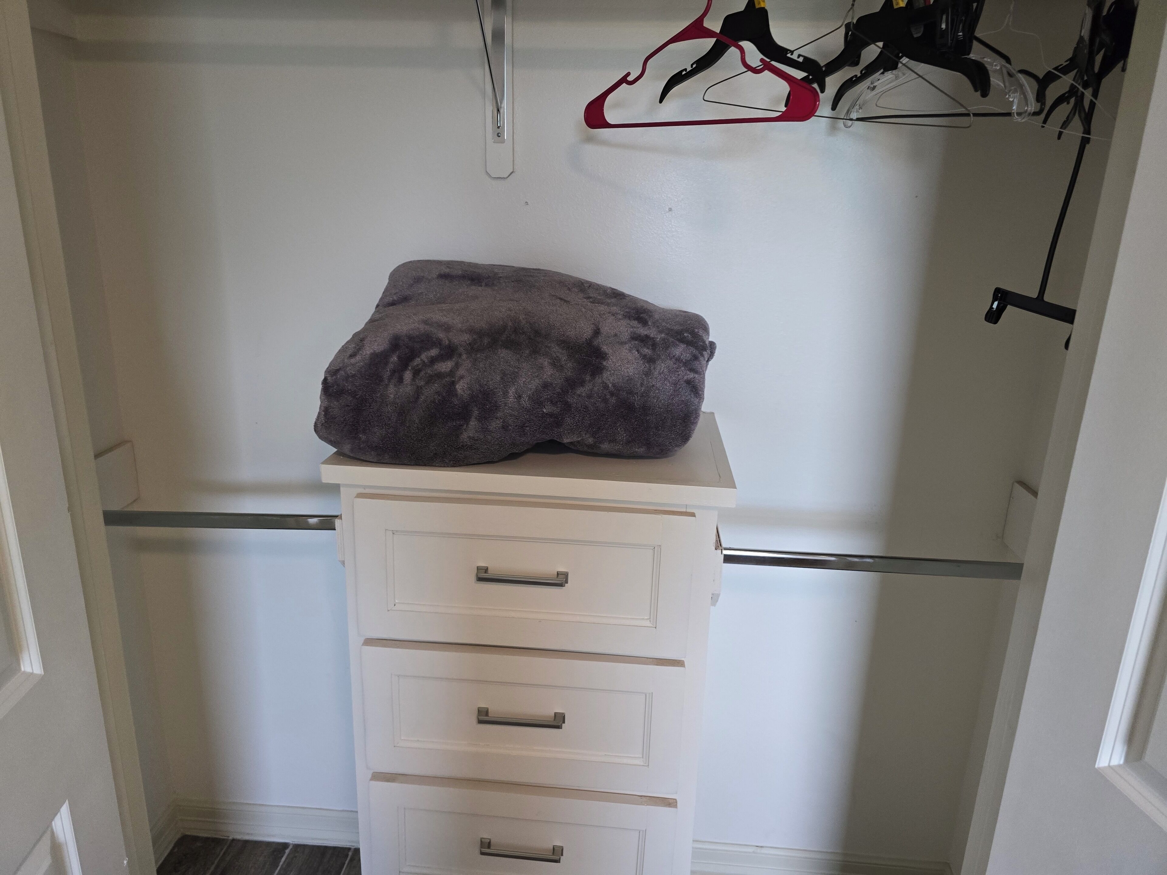 A white dresser with drawers and a gray item on top.