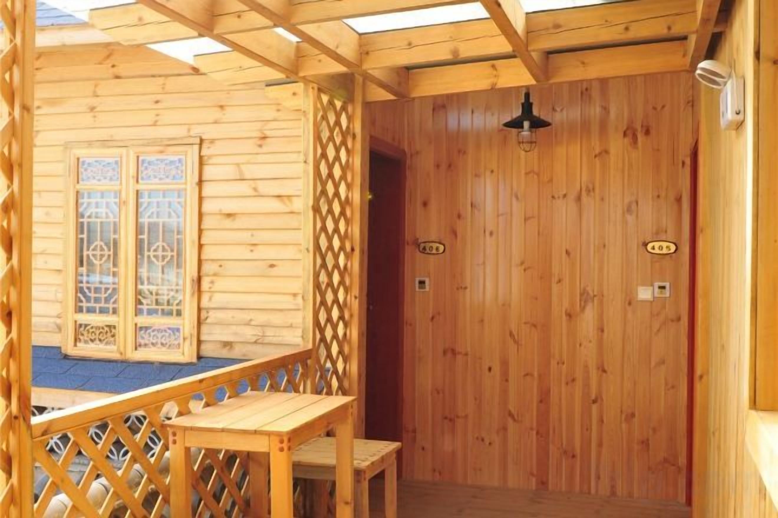 A wooden cabin with a balcony, a door with a number, and a small table.