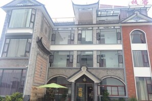 Un edificio a più piani con uno stile architettonico tradizionale, caratterizzato da un ingresso in evidenza con un arco decorativo e un ombrello verde.