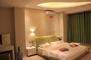 A hotel room with a green bed, white bedding, a bedside table with a lamp, and a wall-mounted air conditioner. - Yiyuan Impression Inn (Eryuan)