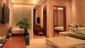 Una habitación de hotel moderna con un escritorio de madera, una planta grande en maceta, un sofá y una cama.
