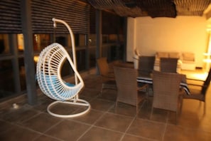 A hanging chair, a dining table, and wicker chairs in a well-lit indoor space. - Yiyuan Impression Inn (Eryuan)